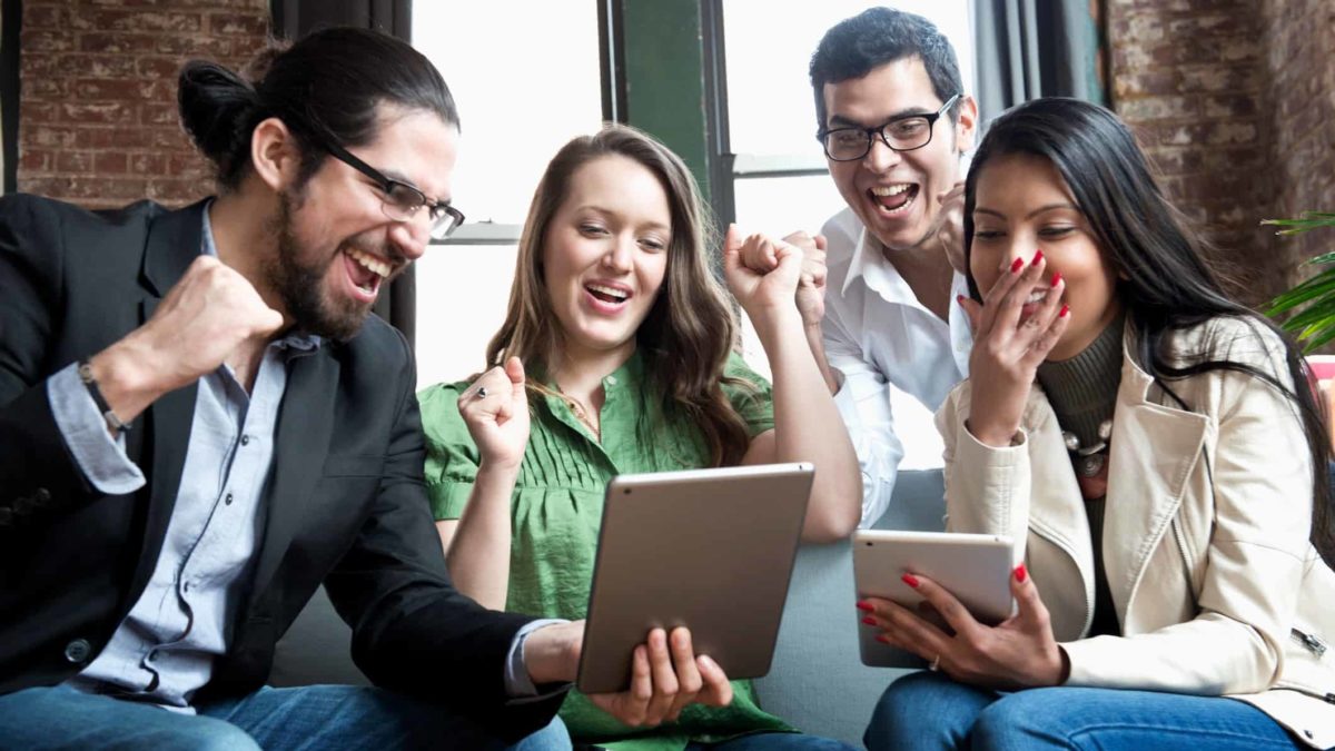 Group of people cheer around tablets in office