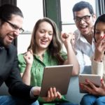 Group of people cheer around tablets in office