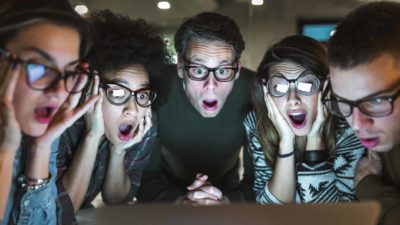Group of shocked people gather around screen