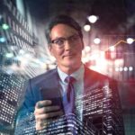 Man holding phone in front of stocks graphic