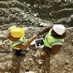 Looking down on two African workers shaking hands over an agreement in an open pit mine.