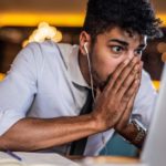 Young man in shirt and tie staring at his laptop screen watching the Paladin Energy share price tank today