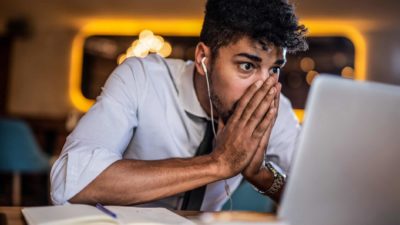 Young man in shirt and tie staring at his laptop screen watching the Paladin Energy share price tank today