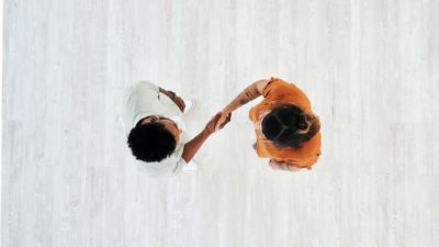 View from above of two young contemporary people shaking hands, agreeing to the deal.