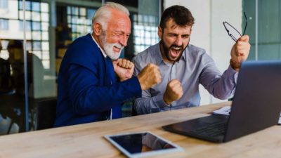 Two men cheering at laptop