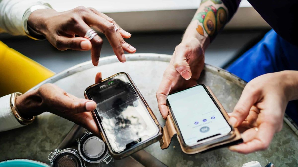 Looking down on a table where two people holding their mobile phones are exchanging information.