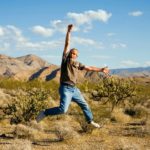 An older man leaping into the air with joy in the Australian outback.