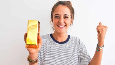 Woman holding gold bar and cheering.