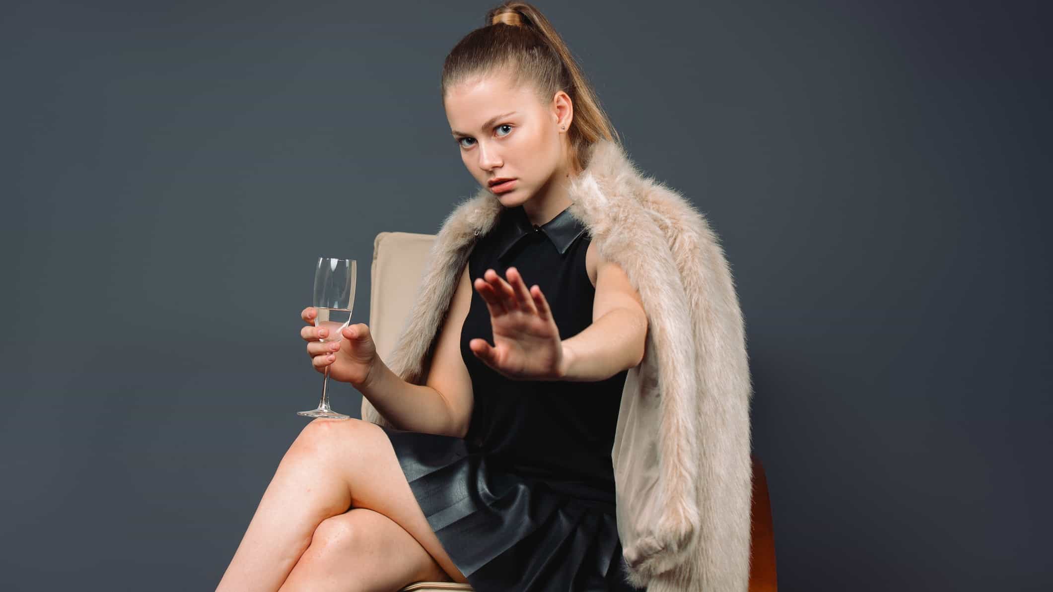 Woman with wine holds out hand to stay stop