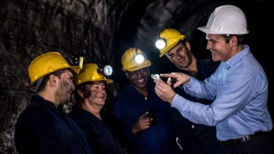happy miners looking at piece of iron ore in underground mine