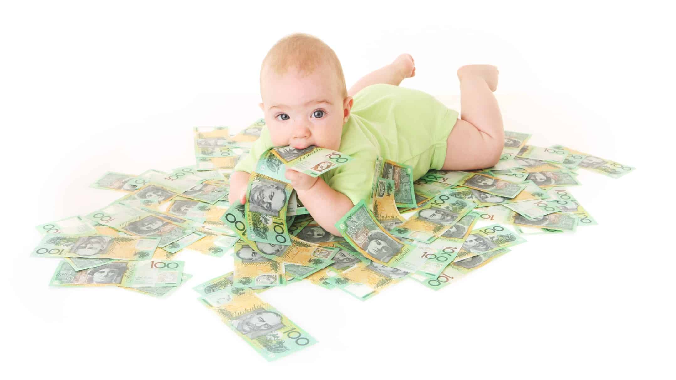 A baby lying on a pile of one hundred dollar notes