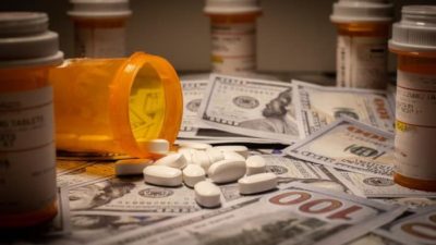 Bottle of tablets spilling over onto piles of US dollars