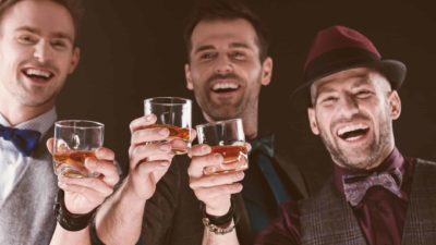 Three men celebrating by drinking glasses of whisky