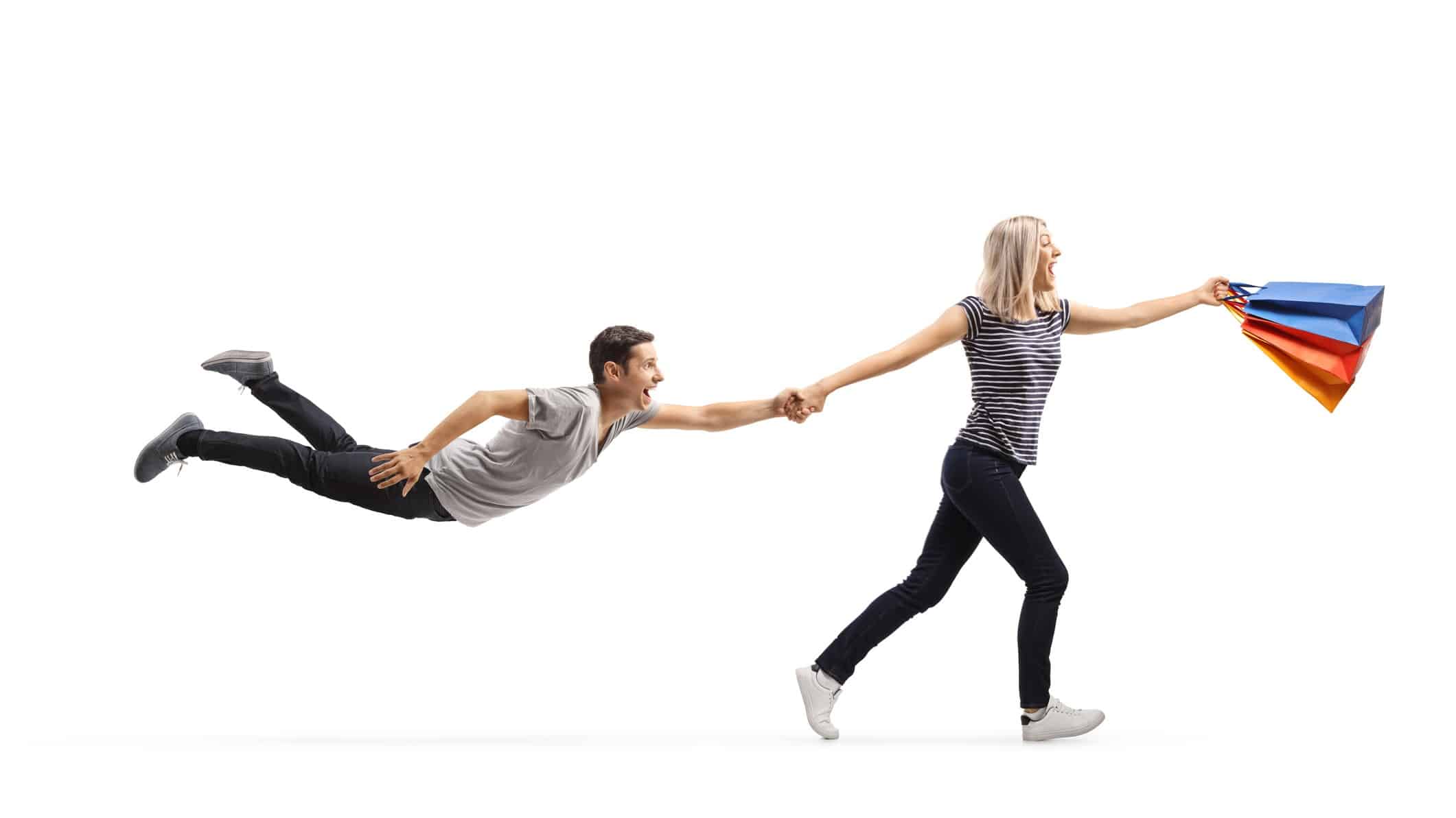 woman with shopping bags pulling man along who is flying in the air