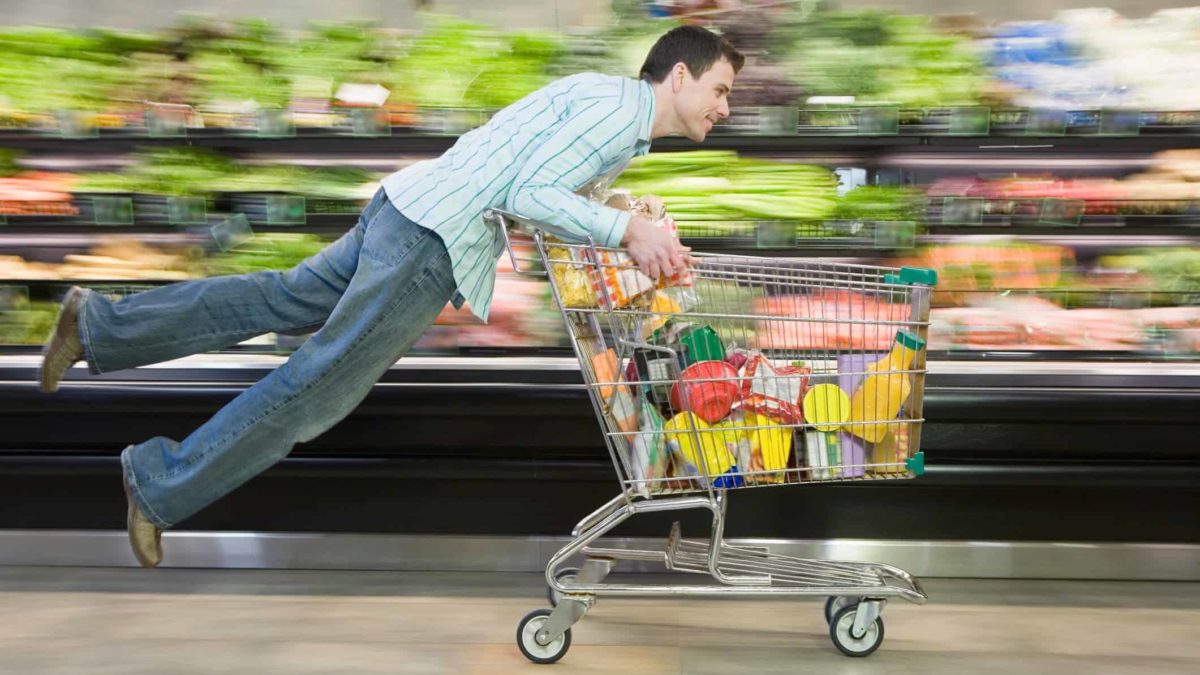 Man racing shopping trolley through supermarket likes coles or woolworths