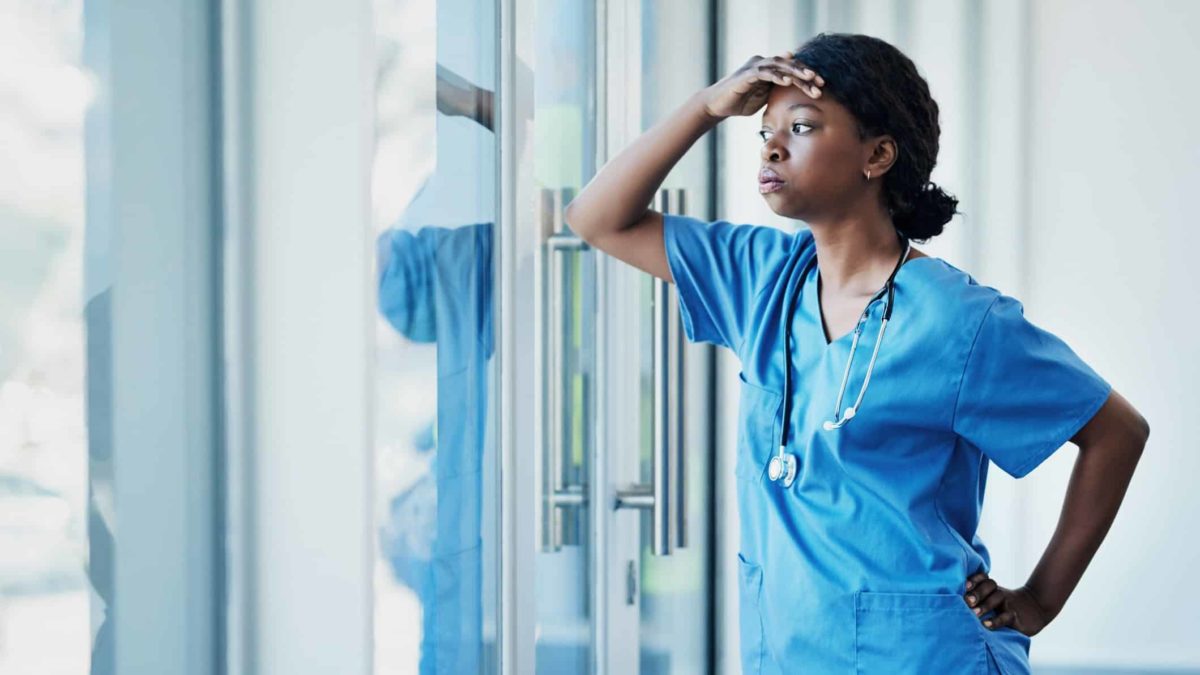doctor looks out window resting head in hand