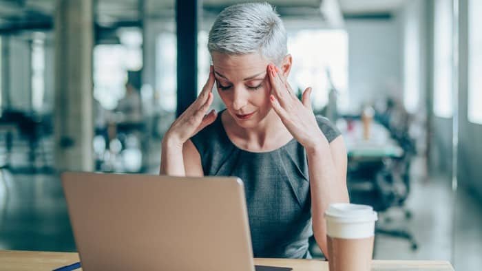 sad, stressed person with head in hands at computer