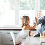 A high-five between father and daughter who are setting up an app on a laptop.