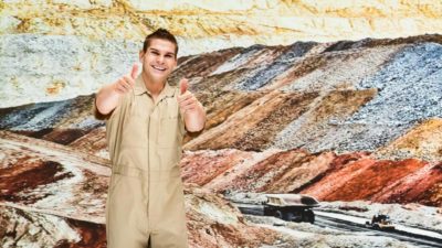 Miner puts thumbs up in front of gold mine quarry