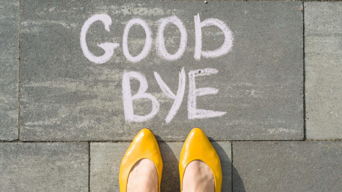 Bird's eye view of a pair of yellow shoes next to a goodbye sign written in chalk on the pavement
