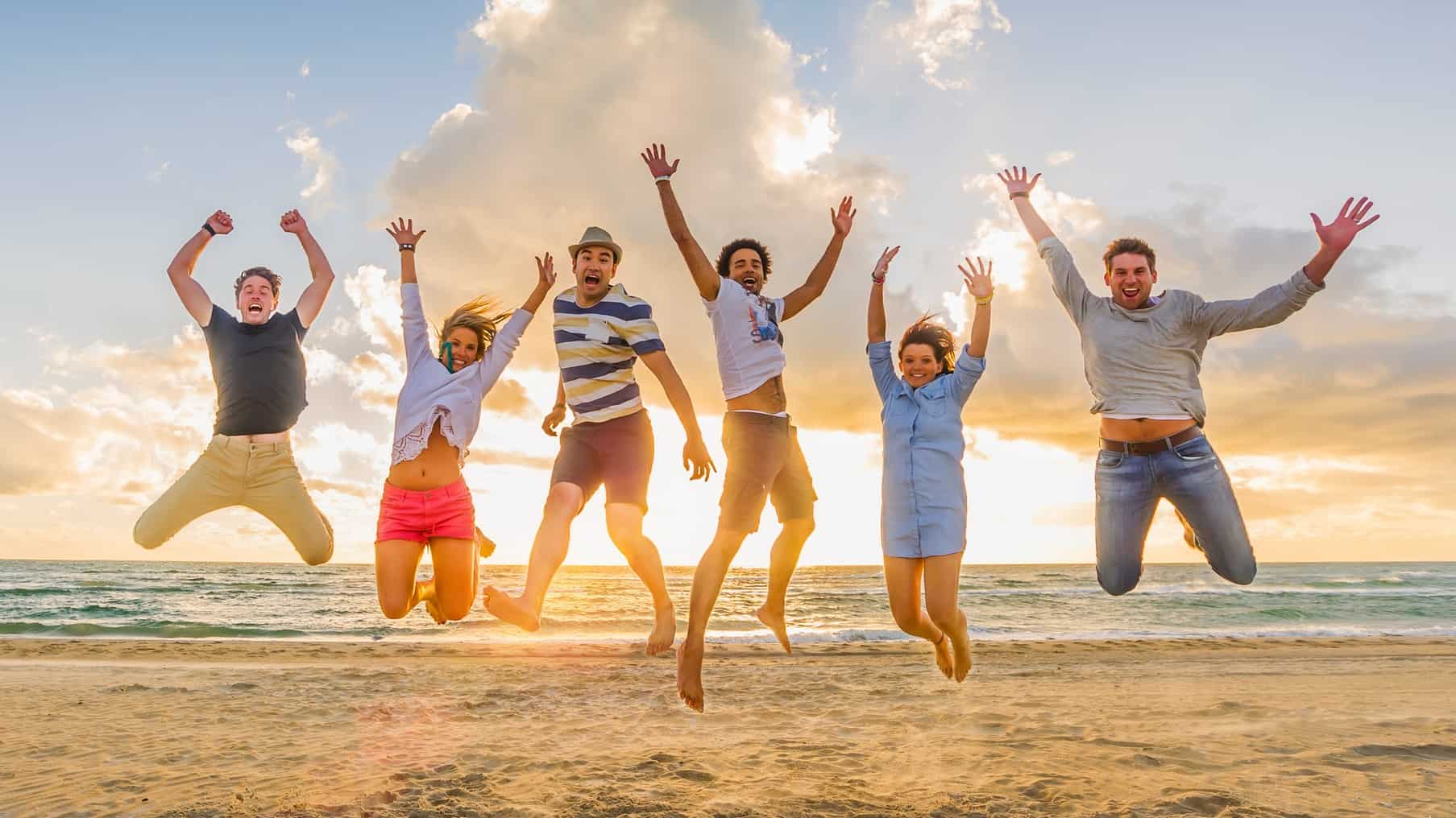 group of friends jump on the beach
