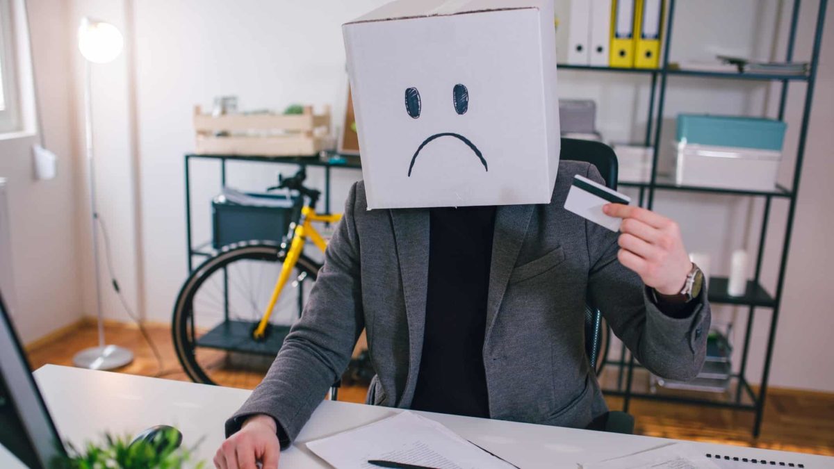 Man with credit card wears box with unhappy face