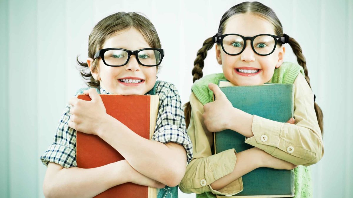 Two children hold on tightly to books hugged against their chests, as if they were holding on to ASX shares for the long term.