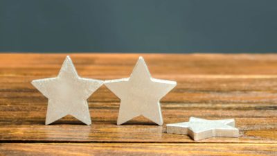 Two wooden stars are lined up on a table with a third lying on its side