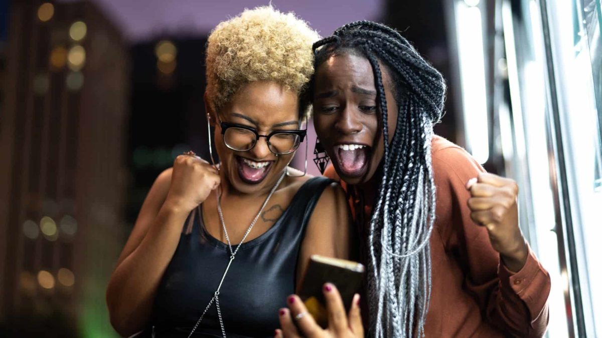 two women celebrating good news on phone