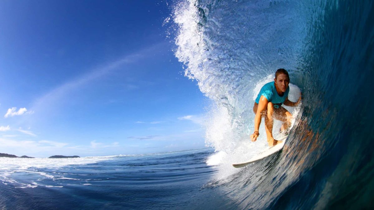 A surfer riding a wave in beautiful clear blue water