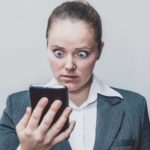 woman looks shocked at mobile phone