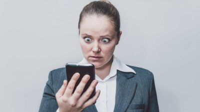 woman looks shocked at mobile phone