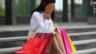 woman with shopping bags sitting on steps with head in hands