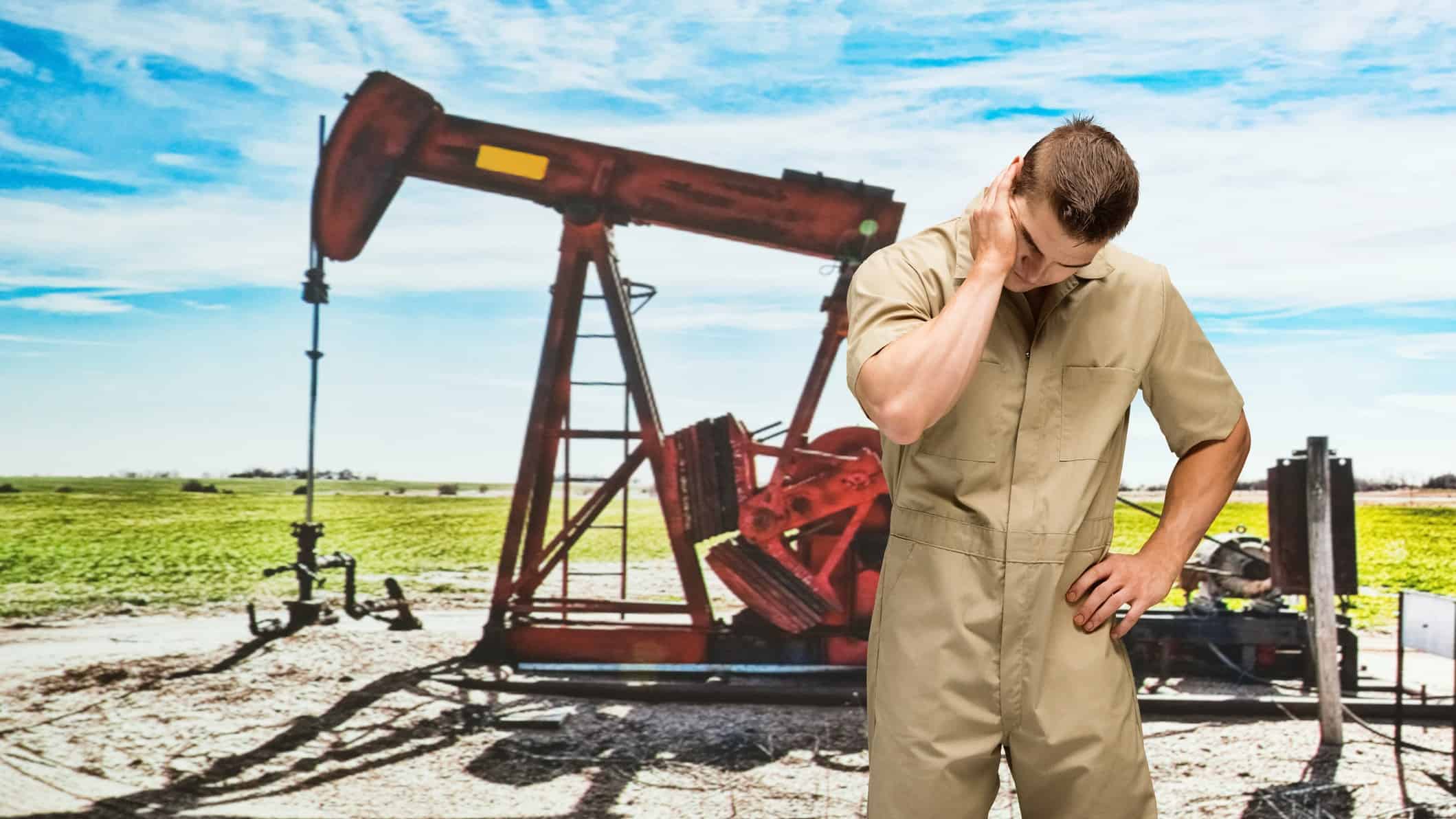 worker with head down at oil drilling site