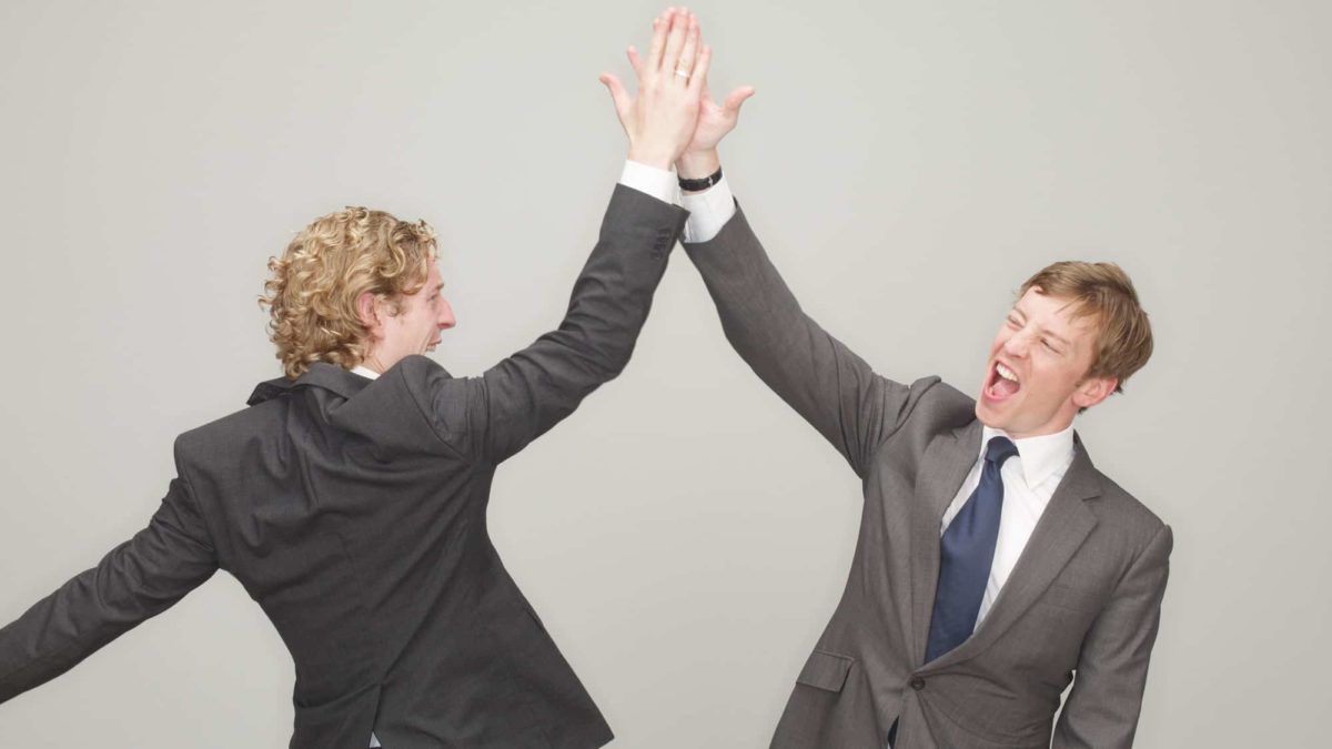 Two businessmen high five each other as the Optus plea to ACCC fails to impact the Telstra share price today