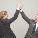 Two businessmen high five each other as the Optus plea to ACCC fails to impact the Telstra share price today