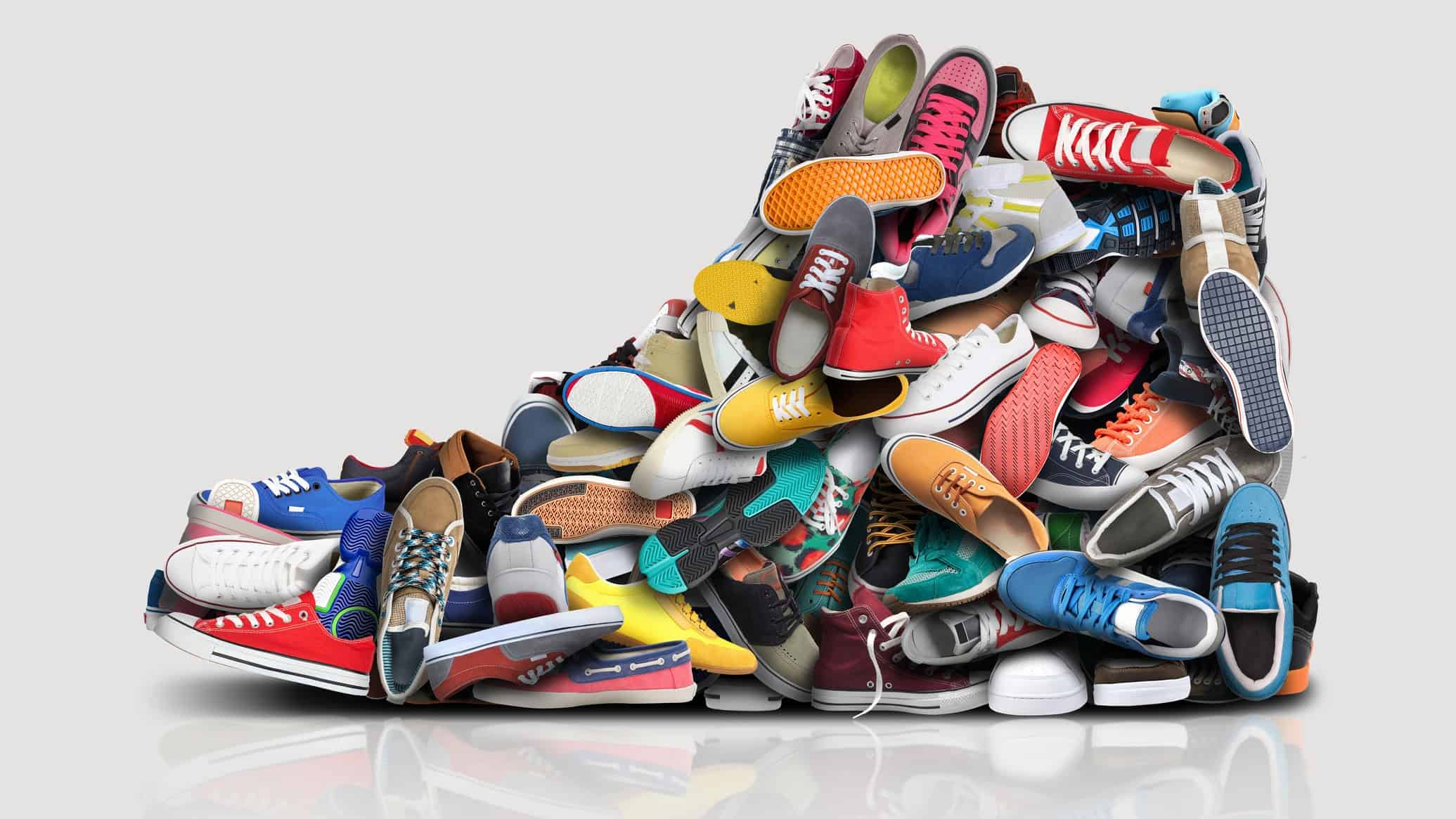a pile of colourful trainer shoes and sandshoes fashioned to look like a large shoe.
