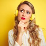 Person with large headphones looking puzzled holding their hand to their chin.