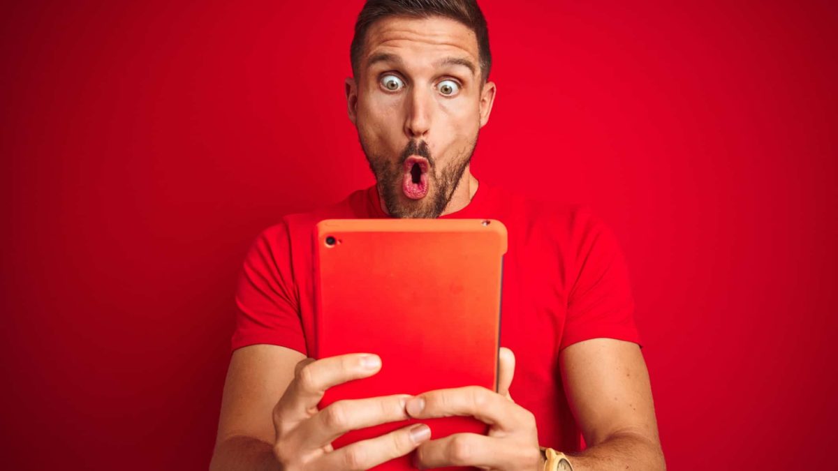 A person with a round-mouthed expression clutches a device screen and looks shocked and surprised.