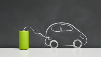 a chalk drawing of a car is connected to a real green battery, signifying clean energy