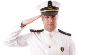 a navy officer in full uniform salutes with hand to temple.