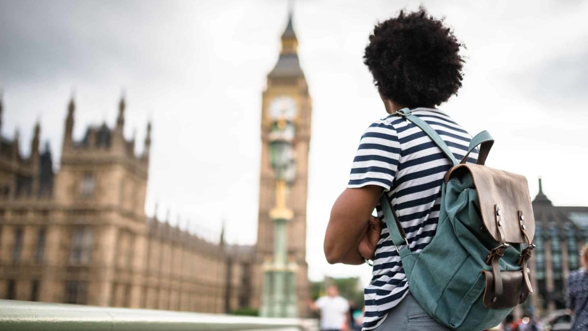 a backpacker stands looking at big ben in London.