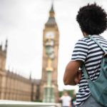 A backpacker stands looking at big ben in London.