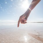 A hand points to a salt crust at a salt mining operation in Australia.