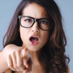 a woman with an aggrieved look on her face points a finger as if in admonishing someone.