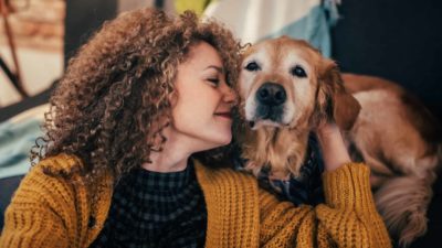 A woman nuzzles her pet dog while working from home.