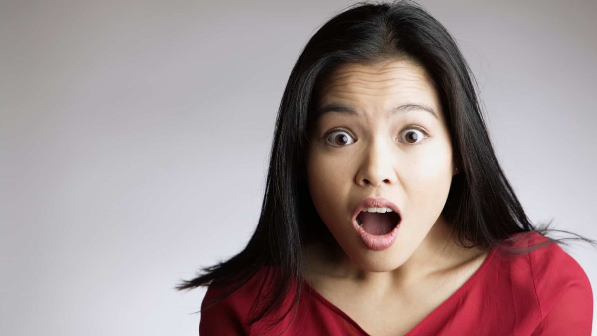 a woman expresses an incredulous look of surprise and shock with wide open eyes and mouth