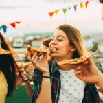 A couple of friends at a rooftop party enjoying some hot and tasty Domino's pizza