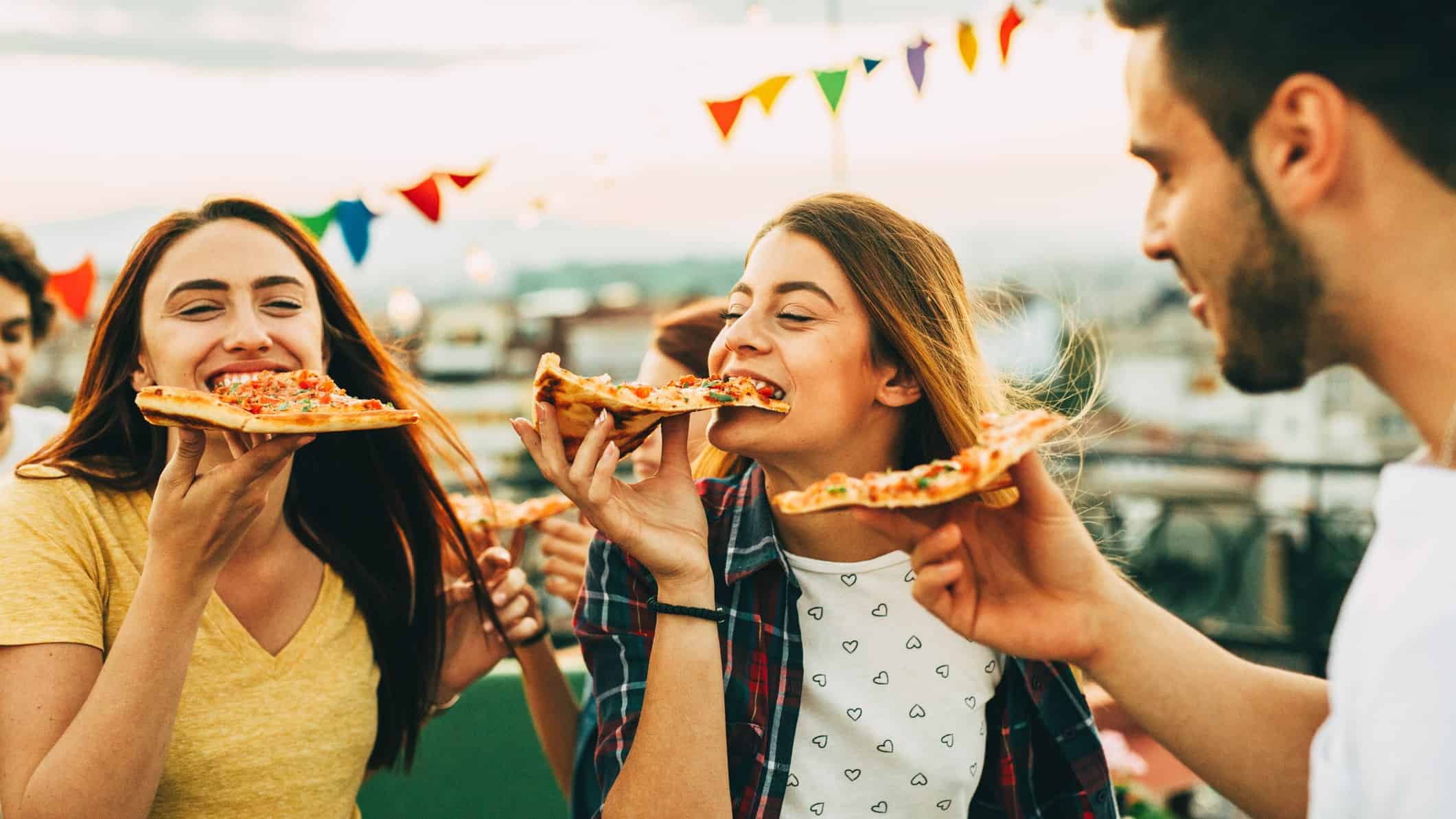 A couple of friends at a rooftop party enjoying some hot and tasty Domino's pizza