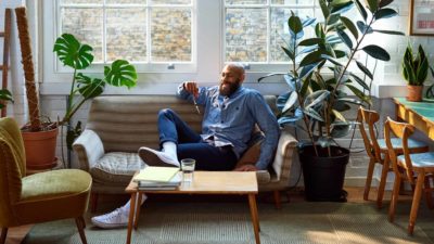 A man eases back onto his sofa, happy with the relaxed vibe from his furniture.